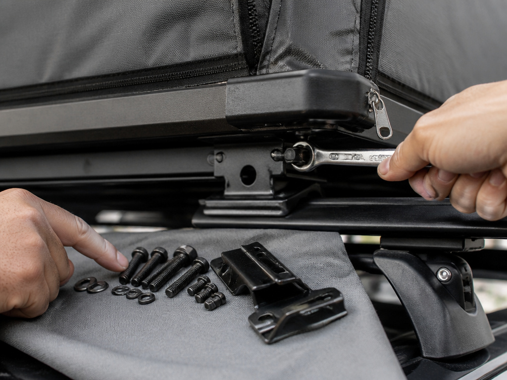 Close-up inspection of rooftop tent mounting hardware and tools during rental pickup.