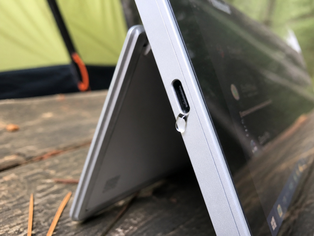 Surface Pro in tent mode with water droplet near vulnerable USB-C port outdoors.