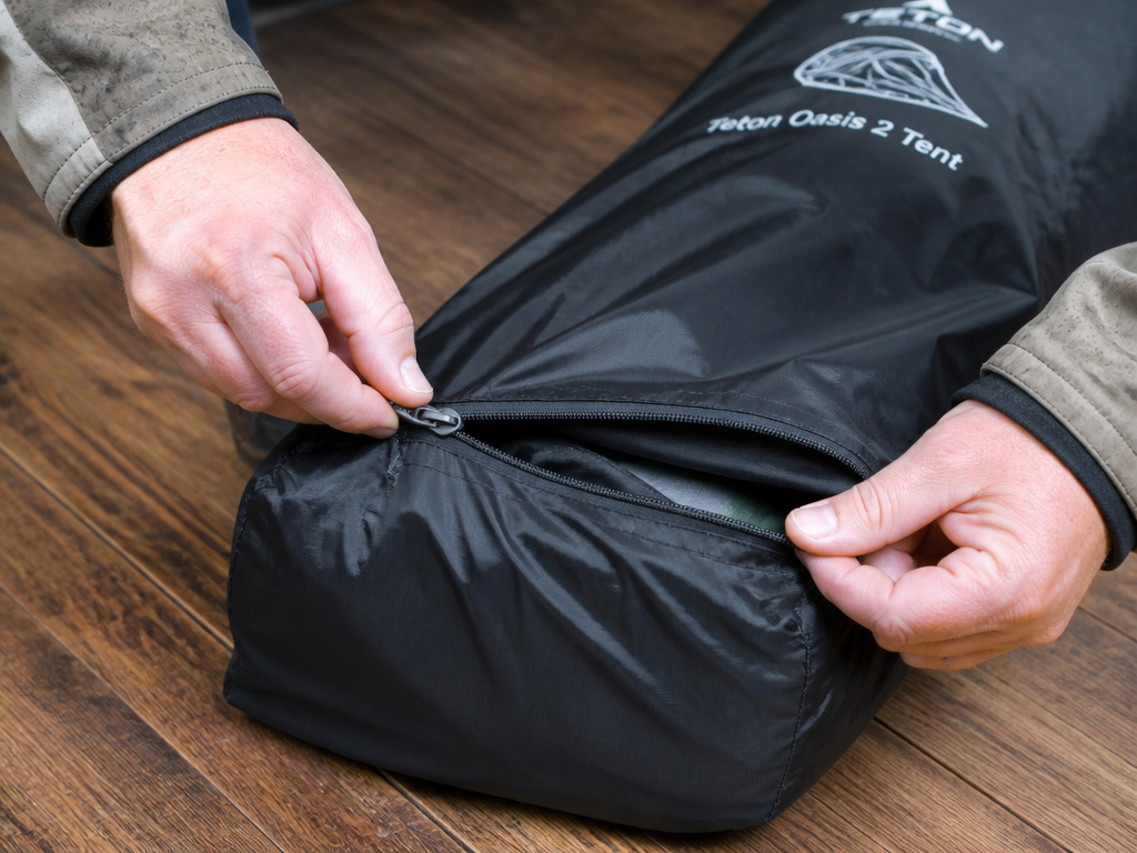 Hands leaving tent storage bag partially unzipped for ventilation