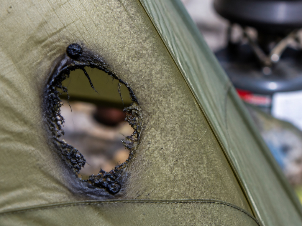 Close-up of a melted hole in a tent vestibule rainfly from cooking accident.