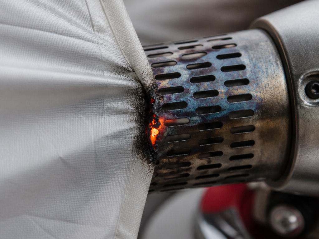 Party tent fabric smoldering against a hot heater exhaust vent