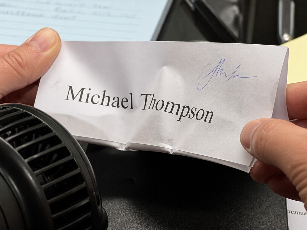 Paper name tent destabilized by airflow from a nearby fan.